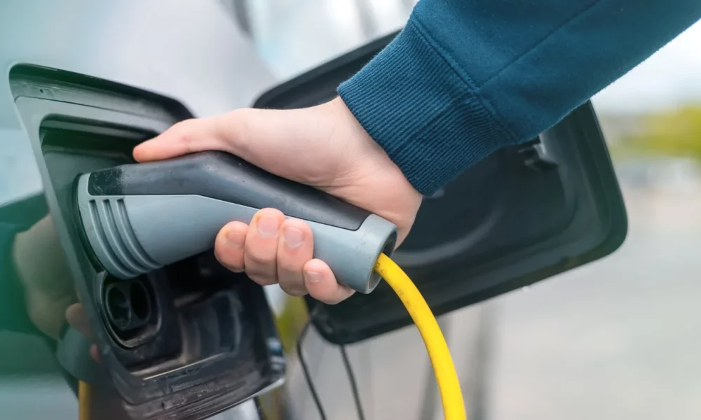 man-plugging-charger-into-electric-car-charge-station